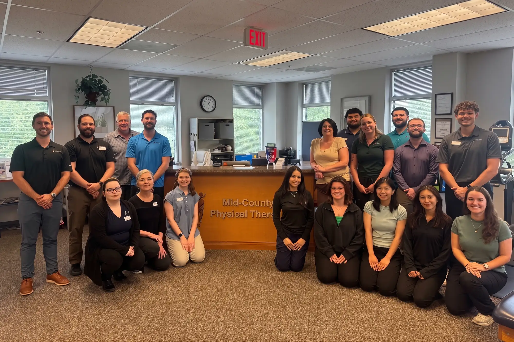 The Mid-County Physical Therapy team standing together at the front desk of their office