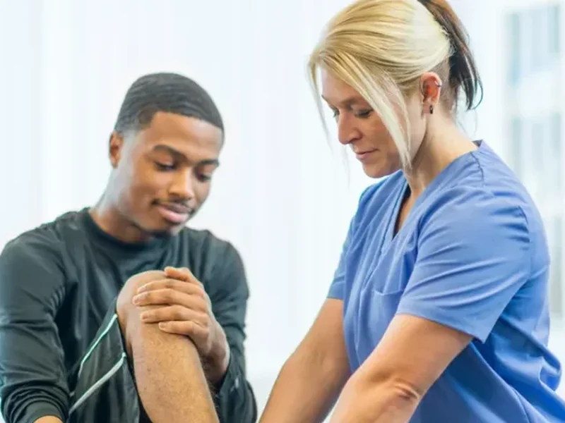 Physical therapist examining a patient's knee during a hands-on evaluation