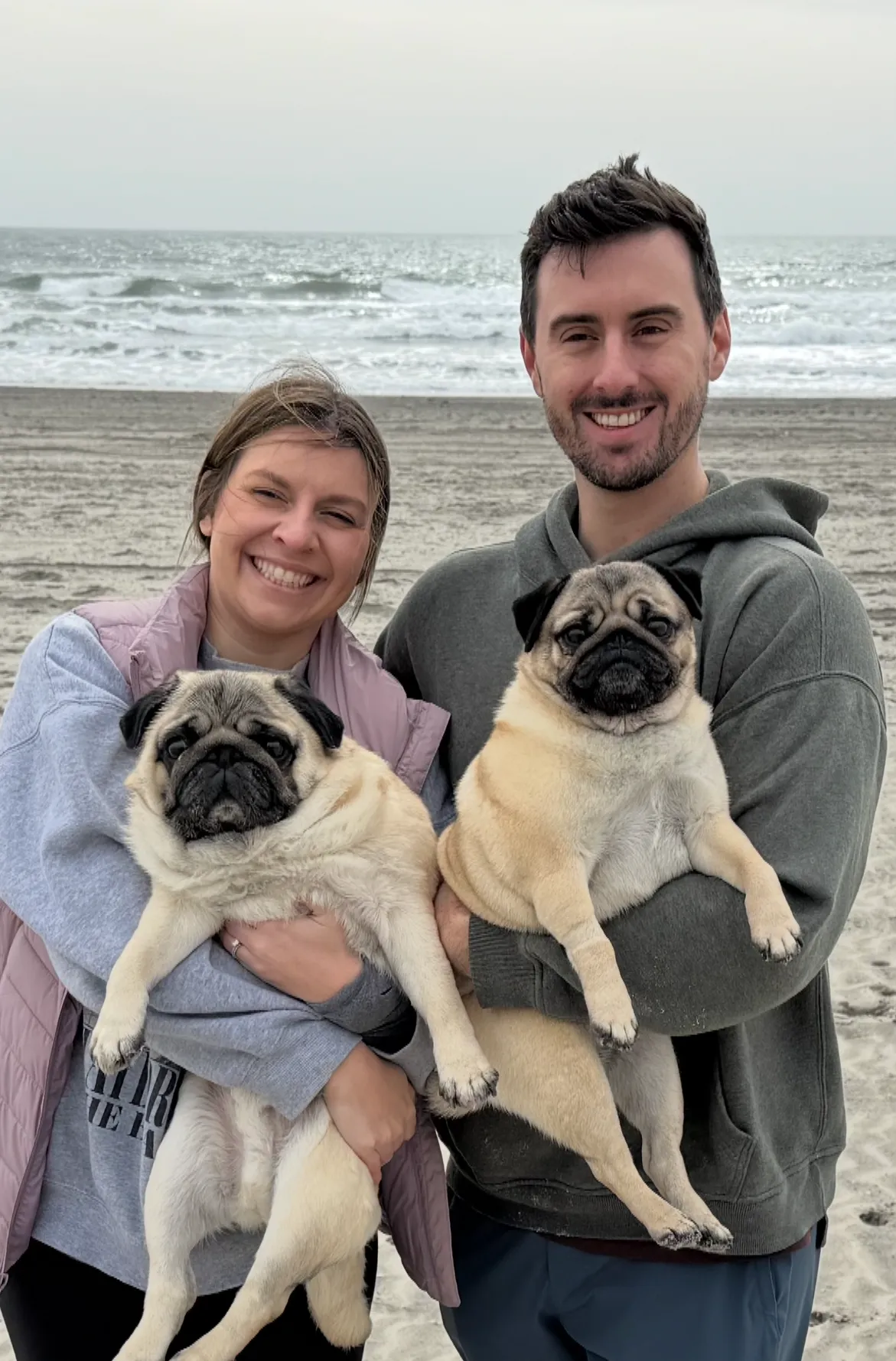 Daniel Mills and his wife with their two pugs at the beach